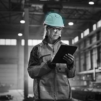 Professional Heavy Industry Engineer Worker Wearing Safety Uniform and Hard Hat, Using Tablet Computer  Serious Successful Female Industrial Specialist Walking in a Metal Manufacture Warehouse 